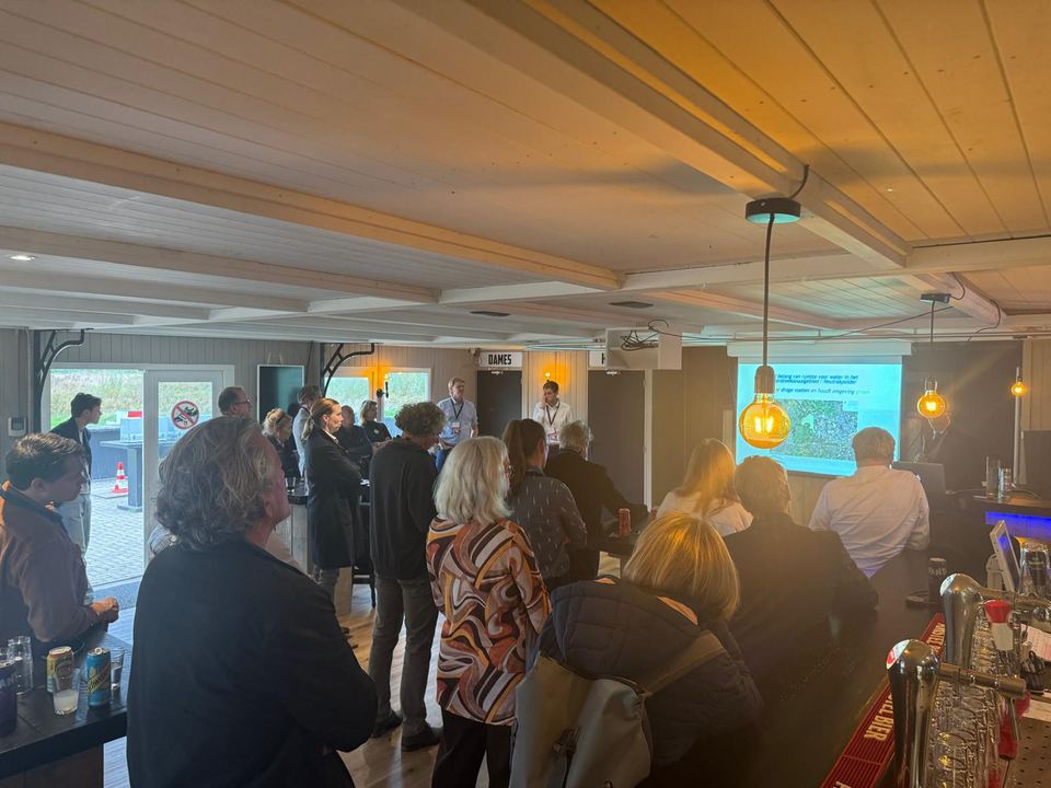 Gasten staan bij de bar tijdens een bijeenkomst in de zaal